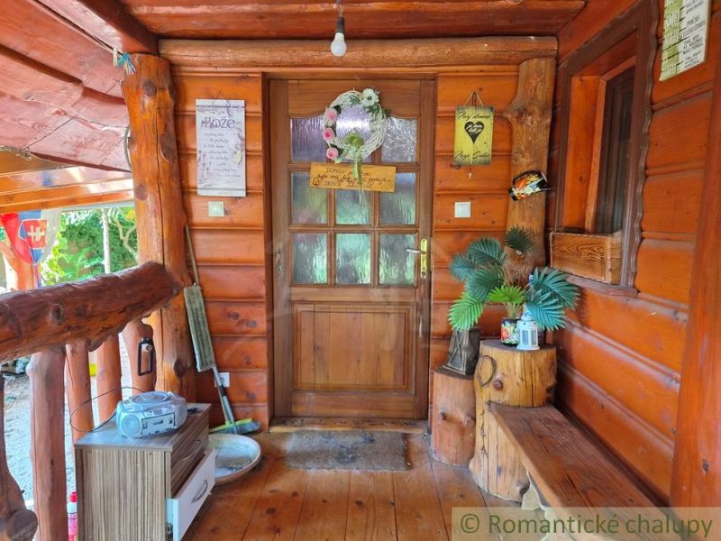 Entrance to a family house with wooden decor in Lehota, adorned with plants and signs.