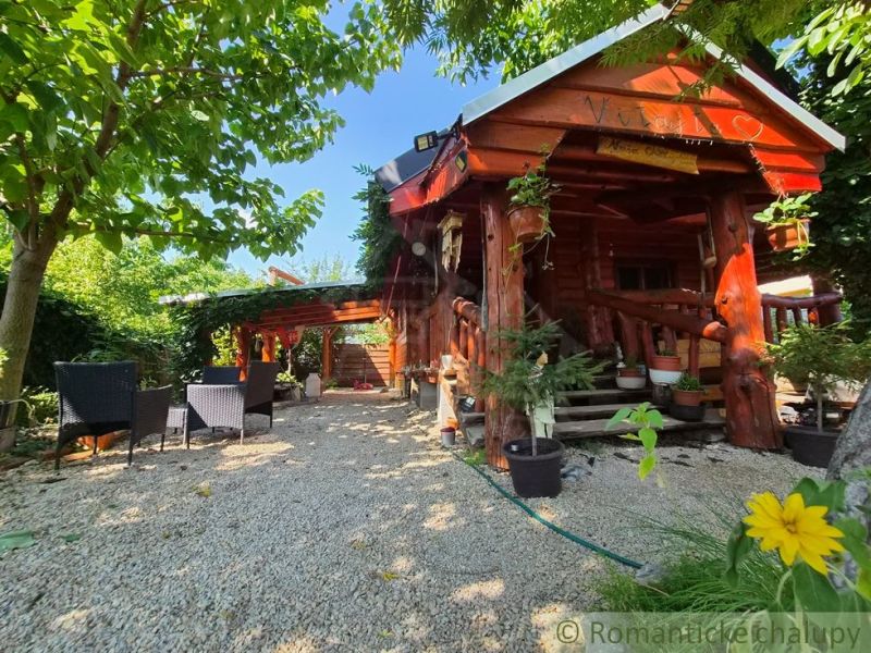 A log family house in Lehota with a terrace and swings surrounded by a garden.
