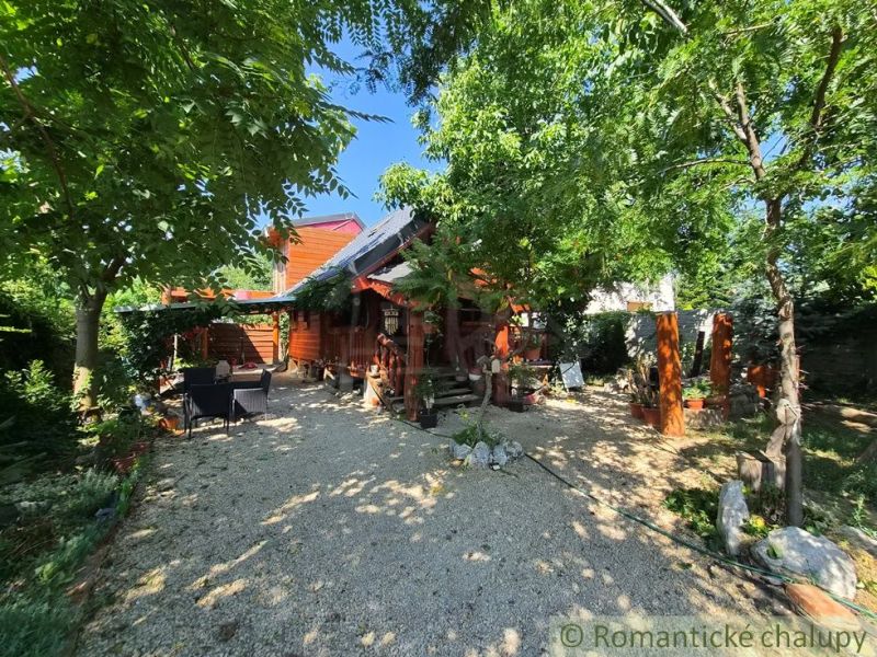 A family house in Lehota surrounded by greenery with a wooden terrace and outdoor seating.