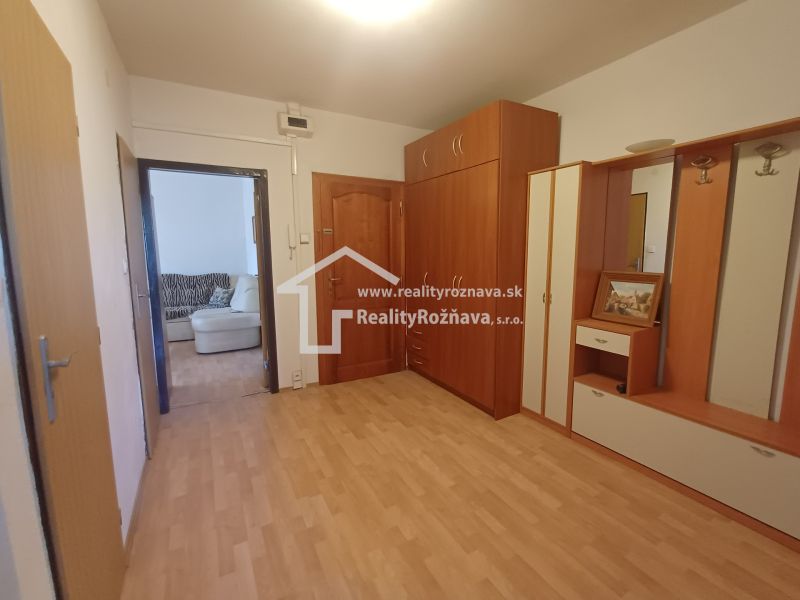 A hallway with a wooden decor floor and furniture in a 3-room apartment.