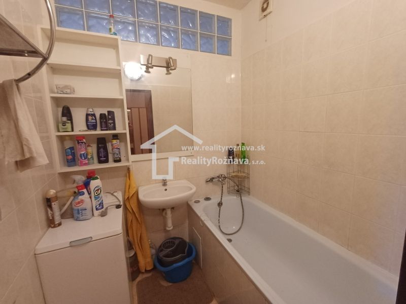 A bathroom in a 3-room apartment with built-in shelves, a sink, and a bathtub.