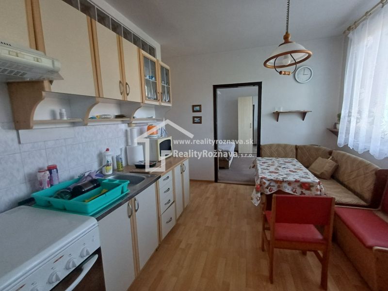 A kitchen in a 3-room apartment with a wooden decor floor and a corner sofa.