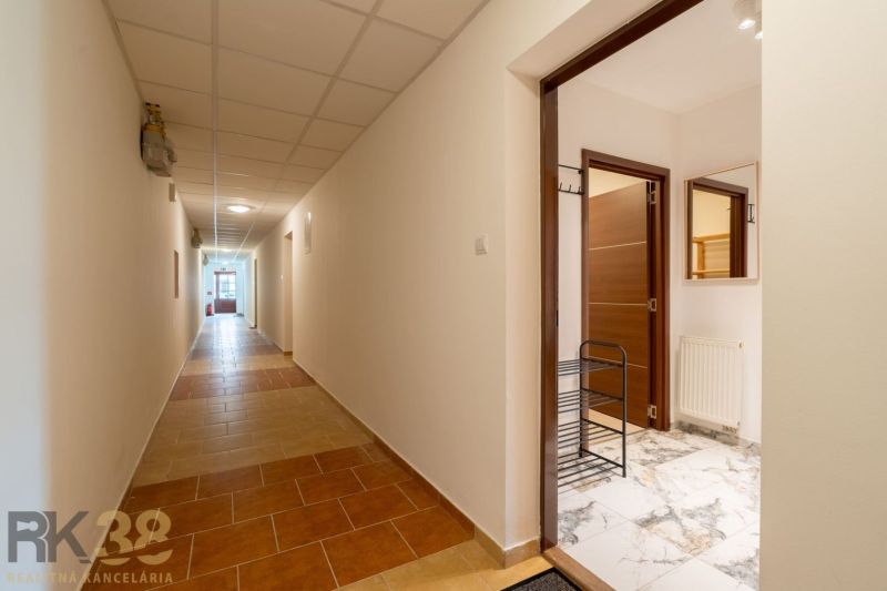 The hallway in Poprad leads to the entrance of a 2-room apartment with a marble floor.