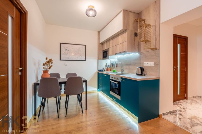 A kitchen in a 2-room apartment with a wooden decor floor and a dining table.
