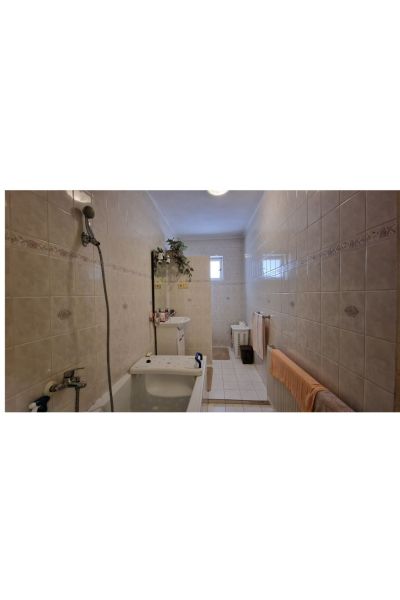 A family house bathroom with a bathtub, sink, and tiles, a distinctive feature of the tiling.