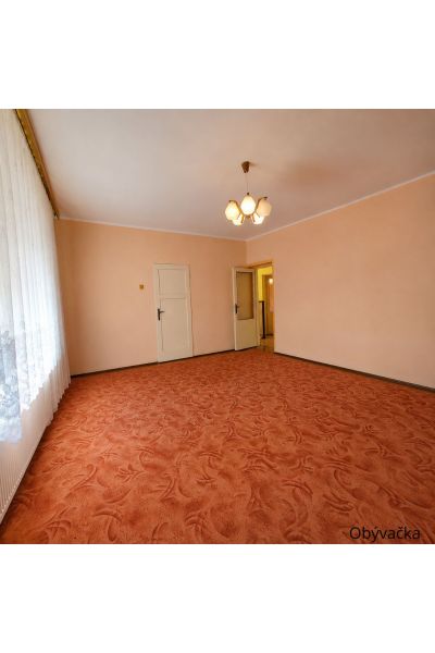 Living room with an orange carpet, white ceiling, and curtain in a family house.