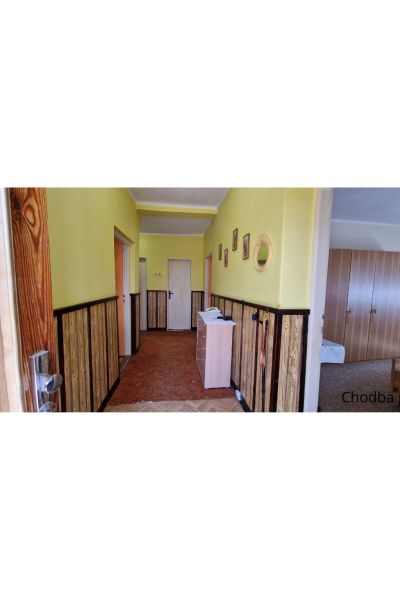 A hallway in a family house with yellow walls and wooden paneling.