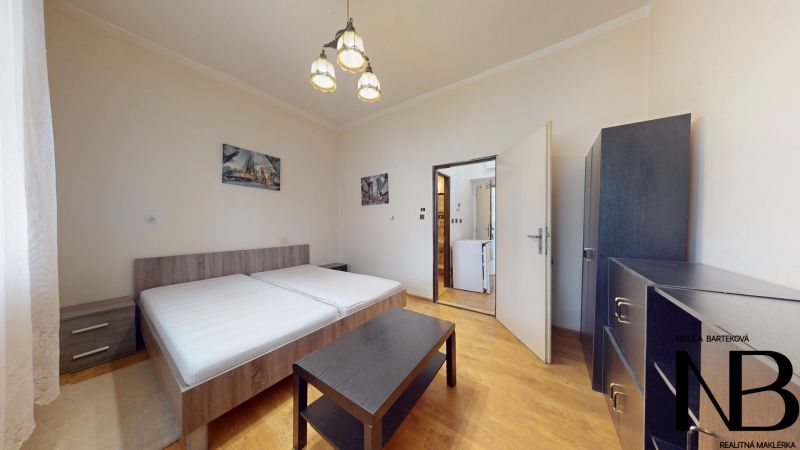 A bright bedroom with a bed, wardrobe, and wooden decor flooring in a studio apartment.