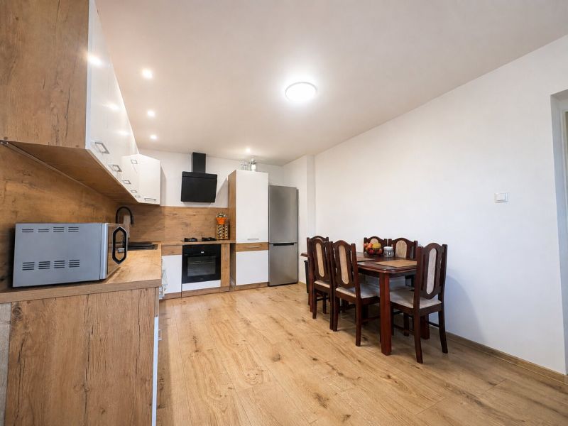A kitchen with a dining table and a wood-patterned floor in a family house.