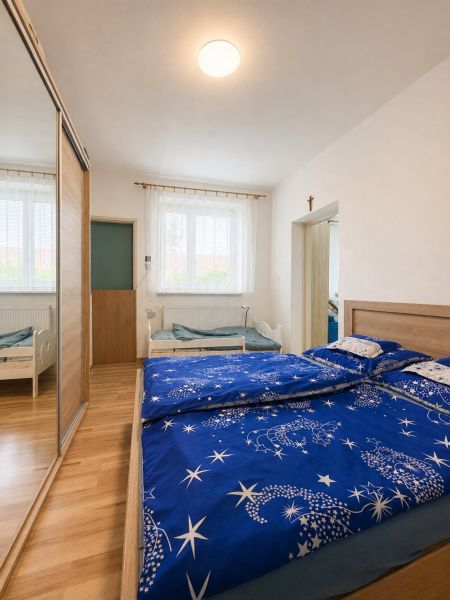 A bedroom in a family house with blue bed linen and a wooden decor floor.