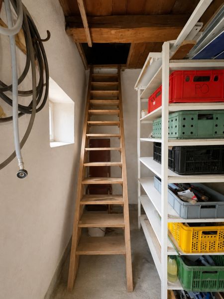 Wooden stairs, shelves with boxes, and hoses in the basement area of the family house.