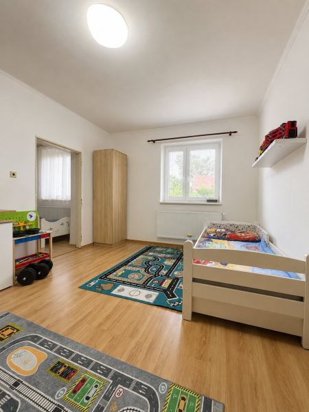 Children's room in a family house with a wooden decor floor, complemented by a carpet with a car track.