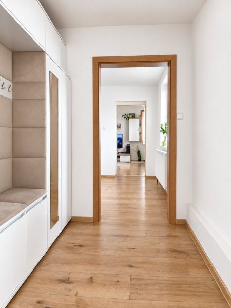 A hallway with a wooden decor floor in a family house, with access to the living room.