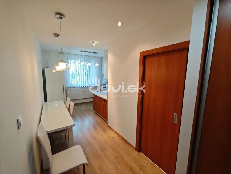 A kitchen in a studio apartment with a bar table and a wooden decor floor.