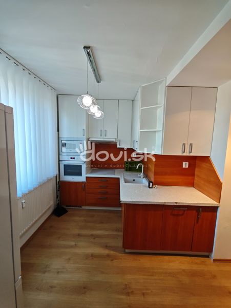 A kitchen in a studio apartment with built-in appliances and a wooden decor floor.