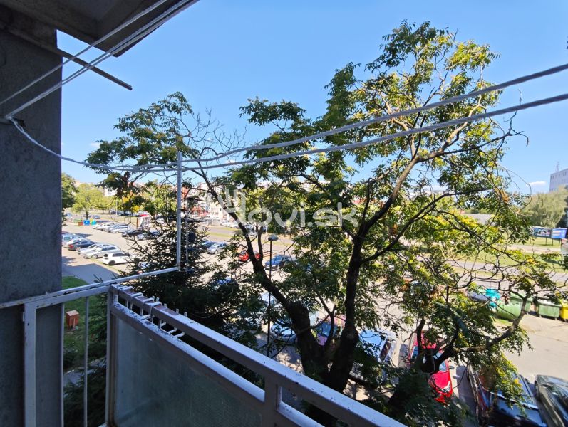 View from the balcony on Hollého Street in Michalovce with a parking lot and trees near a 1-room apartment.