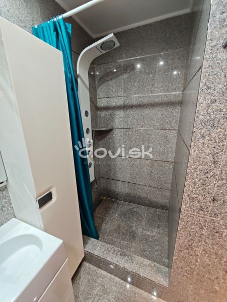 A shower corner with a blue curtain in the bathroom of a studio apartment.
