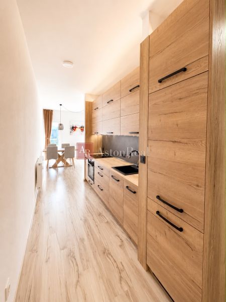 A kitchen in a 3-room apartment with a wooden decor floor and wooden kitchen cabinets.