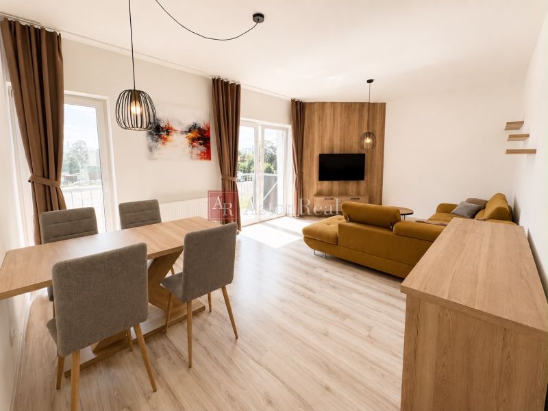 A spacious living room in a three-room apartment with a wooden decor floor and a dining area.