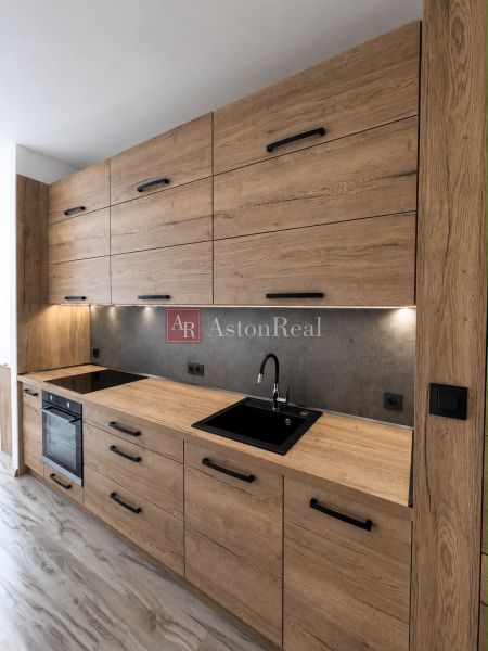 A kitchen in a 3-room apartment with a wooden decor kitchen unit and a cooktop.