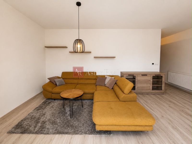 Living room in a 3-room apartment with a mustard-colored sofa, wooden decor flooring.