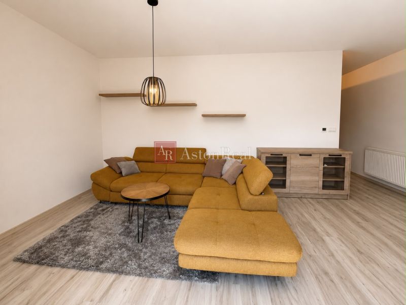 Living room with a sofa and wood-patterned flooring in a three-room apartment.
