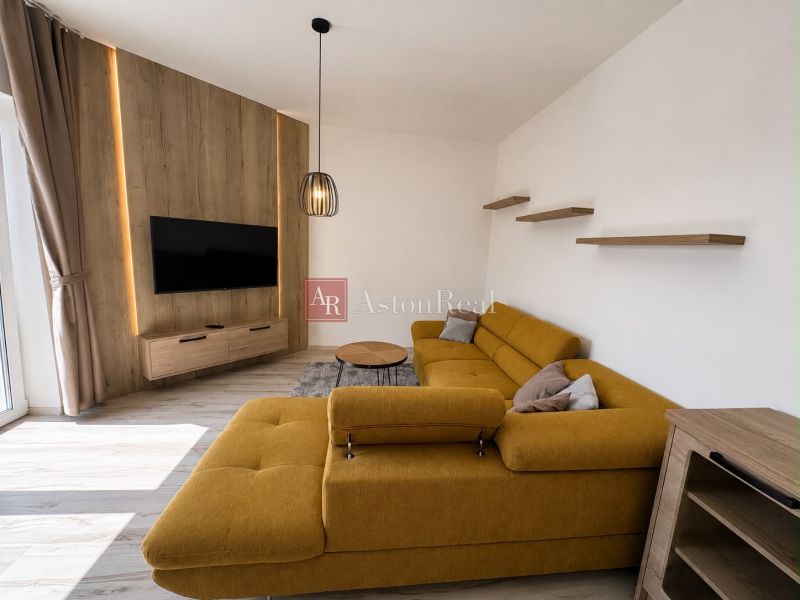 Living room with a mustard sofa, television, and wooden decor flooring.