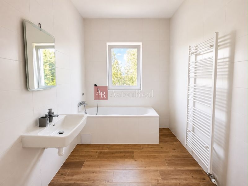 A bathroom with light walls, a bathtub, a sink, and a wooden decor floor, suitable for a 3-room apartment.