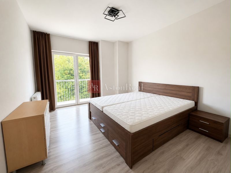 Bedroom with wood-patterned flooring in a 3-room apartment, light and view of greenery.