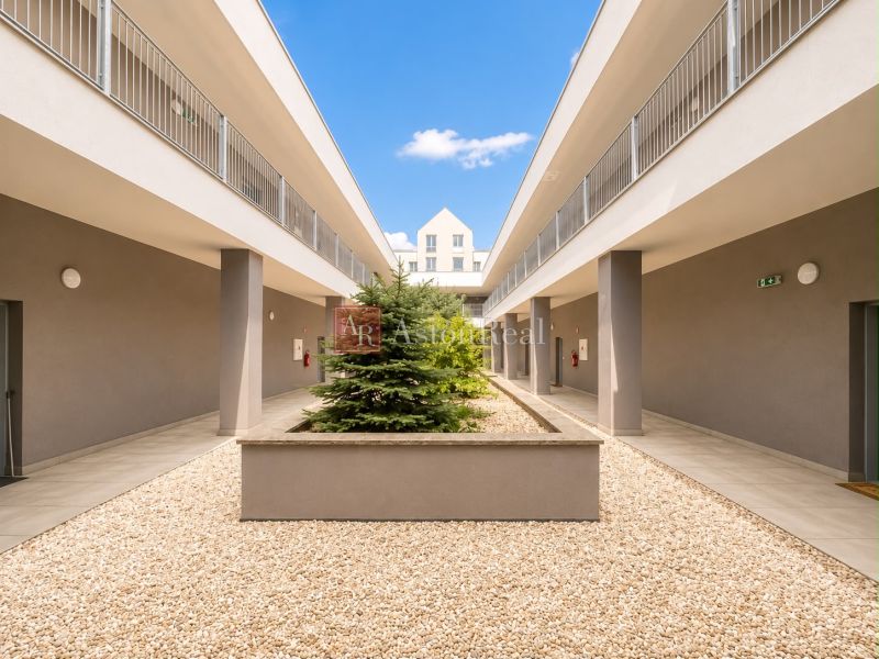 Entrance courtyard of a 3-room apartment in Liptovský Mikuláš with greenery and gravel surface.