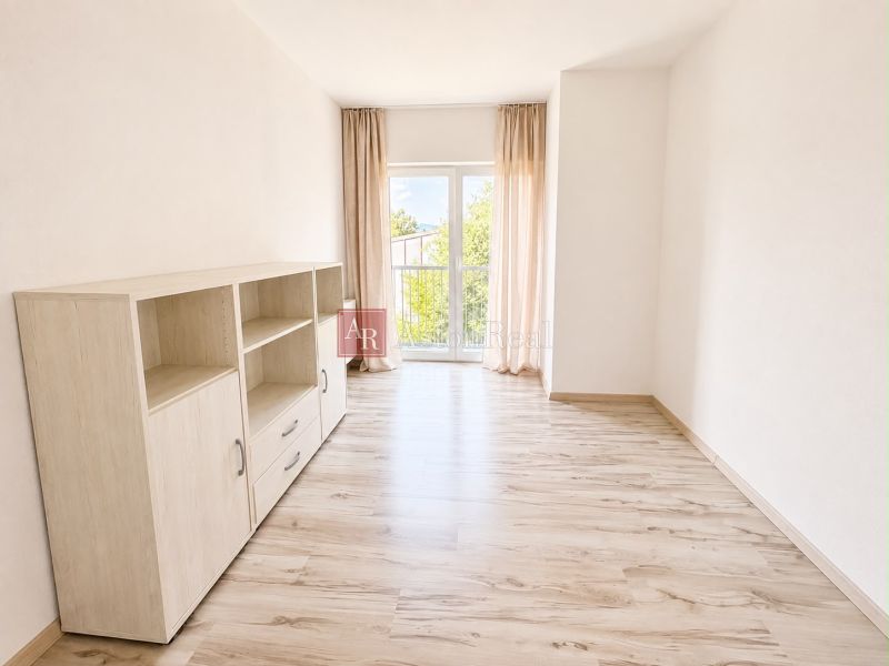 A bright room with a wood-patterned floor and a cabinet in a 3-room apartment.