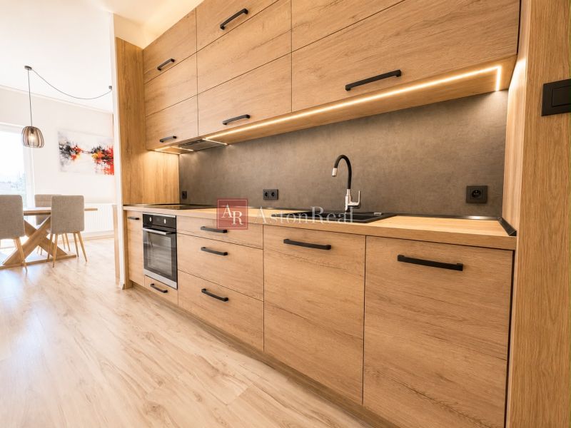 A kitchen in a 3-room apartment with a wood-patterned floor and a dining area.