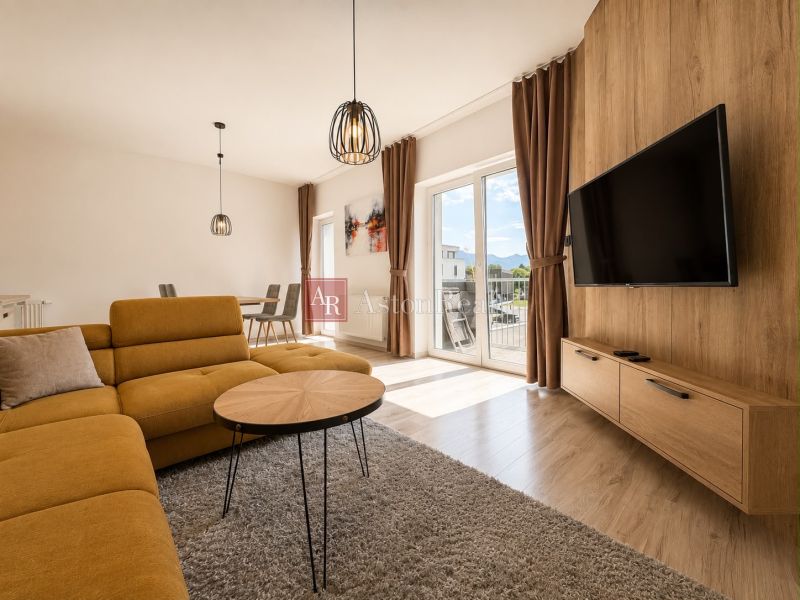 Living room in a 3-room apartment with a sofa, table, TV, and floor with a wooden decor.
