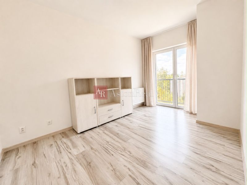 A room with a wooden decor floor and light furniture in a 3-room apartment.