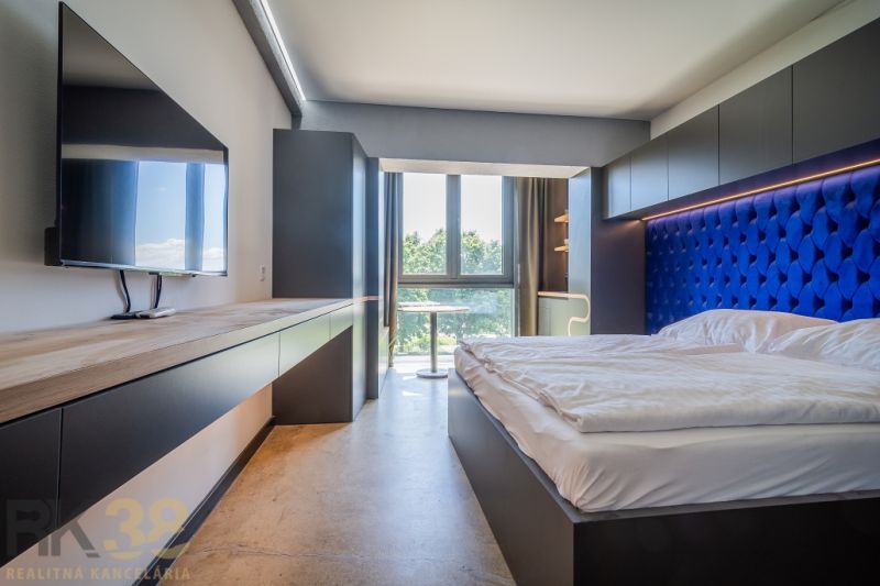 Bedroom in a holiday apartment with a bed and TV, large window provides a view.