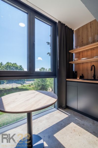 Kitchen corner in a holiday apartment with a window and wooden shelves.