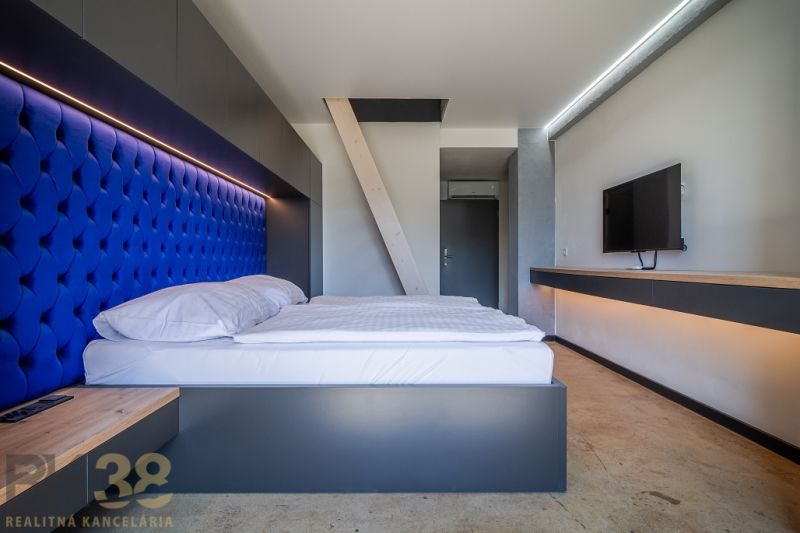 Bedroom in a holiday apartment with a blue headboard and a TV on the wall.