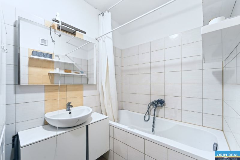 Bathroom with a bathtub and a sink in a 3-room apartment with tiles and tiling.