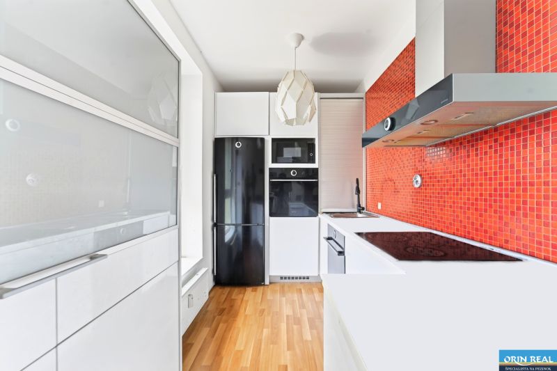 A kitchen in a 3-room apartment with orange mosaic and a wooden decor floor.