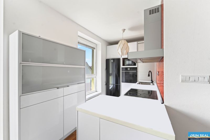A bright kitchen with white furniture and black appliances in a 3-room apartment.