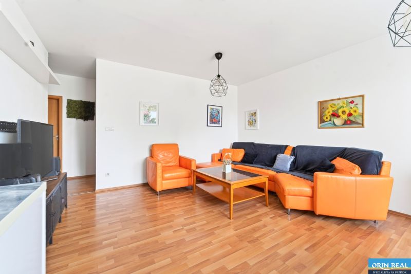 Living room in a 3-room apartment with an orange sofa and a floor with a wood design.