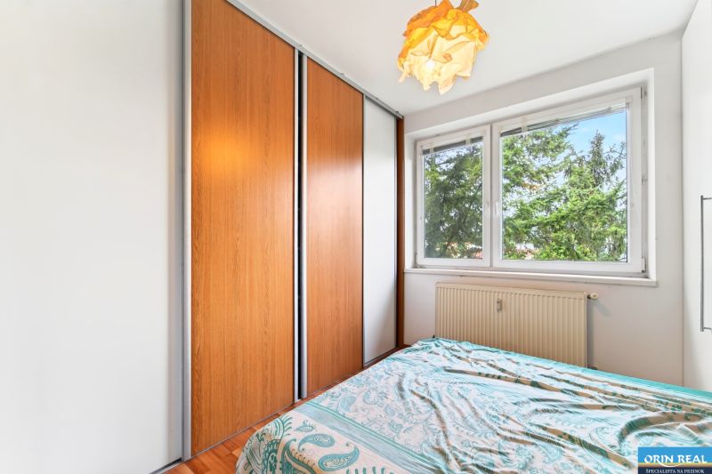 A bedroom with a large wardrobe, a bed, and a window in a 3-room apartment.
