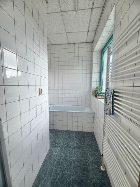 A bathroom with white tiles and a bathtub in the offices.