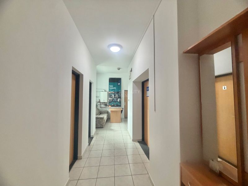 A hallway in offices with a tiled floor and doors to various rooms.
