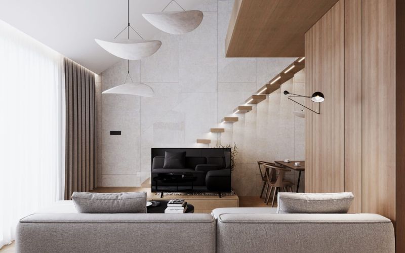 Living room in a studio apartment with a TV, stairs, and a wooden decor floor.