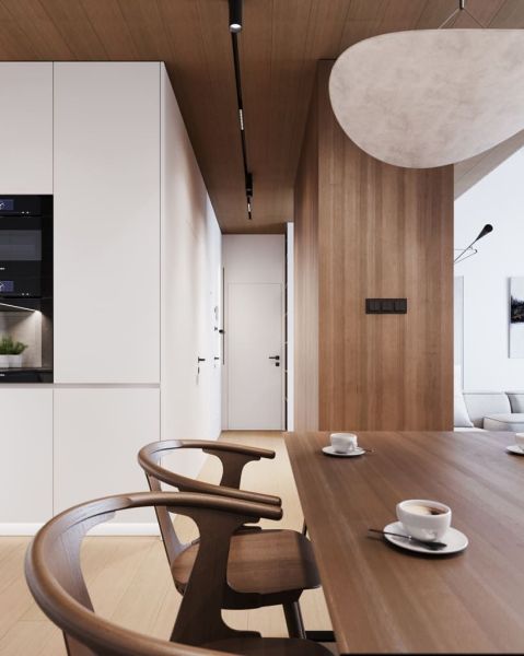 Dining area with wooden decor in a studio apartment, view of the kitchen and hallway.