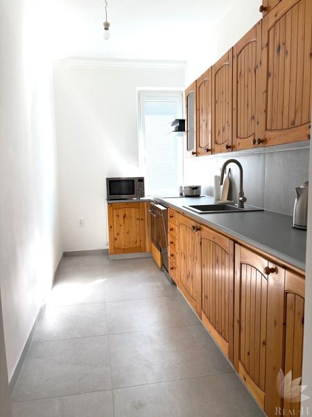 A kitchen in a 3-room apartment with wooden cabinets and ceramic tiles.