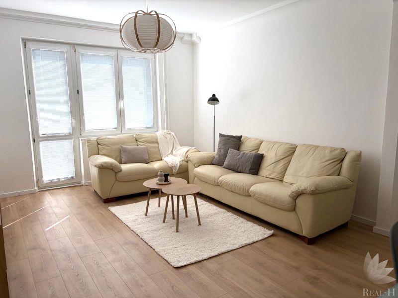 Living room in a 3-room apartment with light furniture and a wooden decor floor.