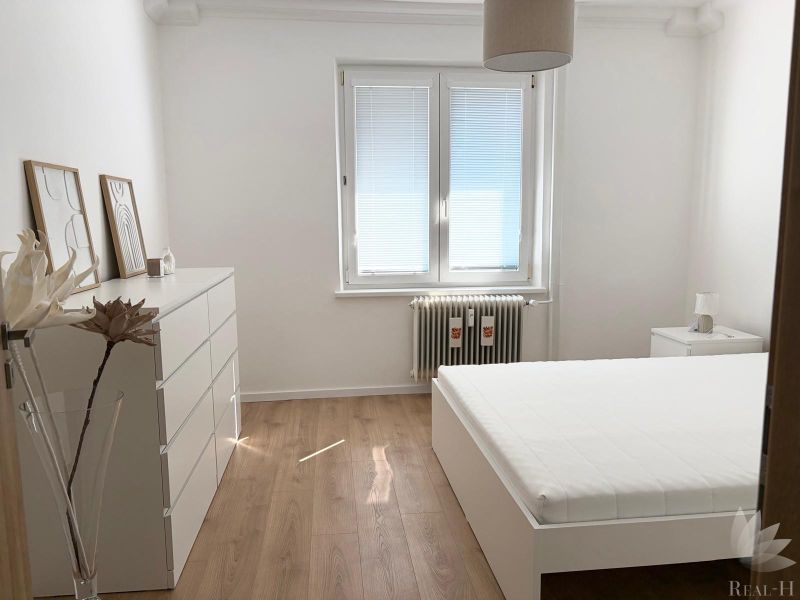 Bedroom in a 3-room apartment with a bed and a wooden decor floor.