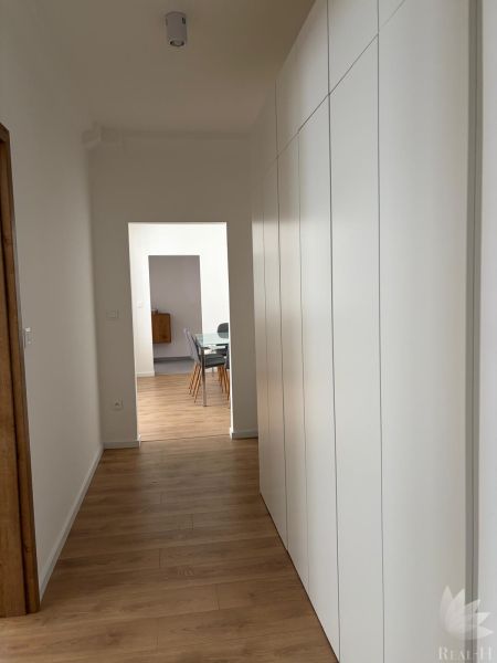 A hallway with a wood-patterned floor and built-in wardrobes in a 3-room apartment.